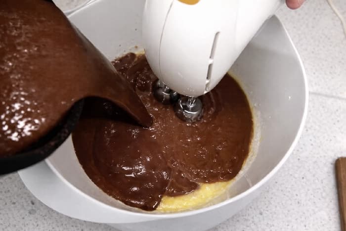 Den avkjølte sjokoladeblandingen helles i bollen med egg, sukker og rømme.