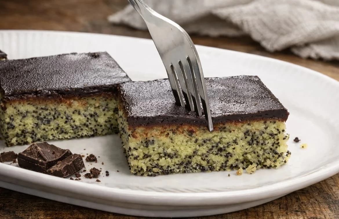 Saftig valmuekake med sjokoladeglasur, skåret i biter og servert på et hvitt fat.