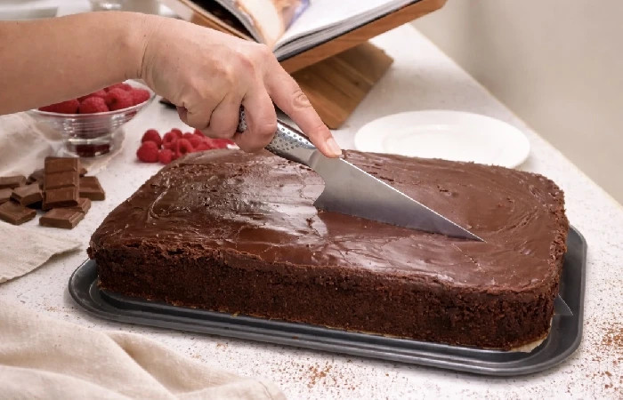 Sjokoladekake med glasur som skjæres i jevne stykker.