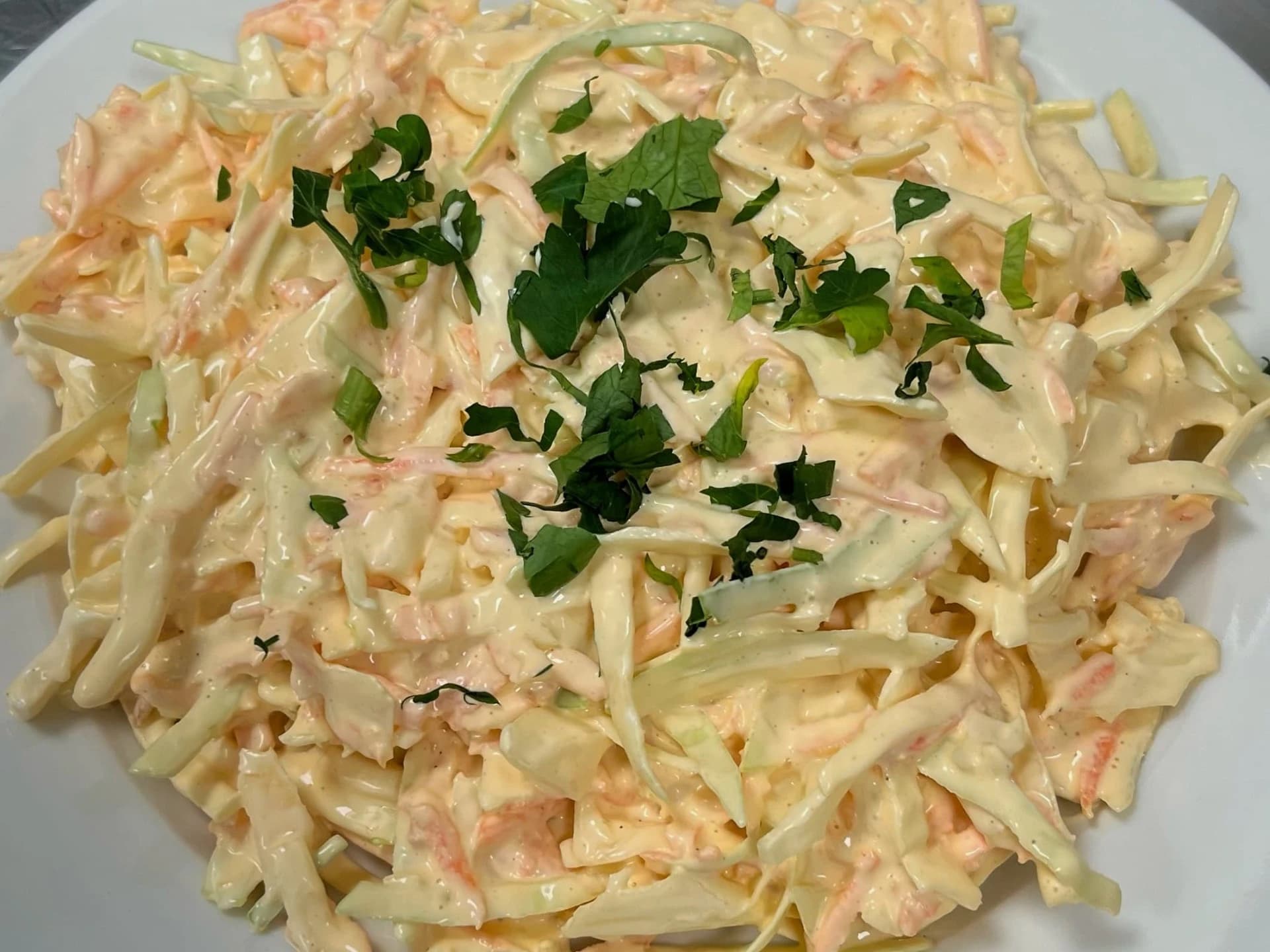 Kremet coleslaw med finsnittet kål, revet gulrot og frisk persille.