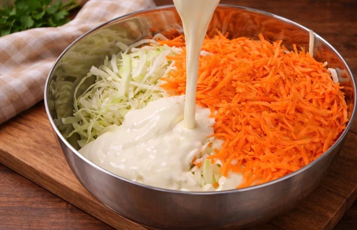 Finsnittet hodekål og revet gulrot blandet med kremet dressing til coleslaw.