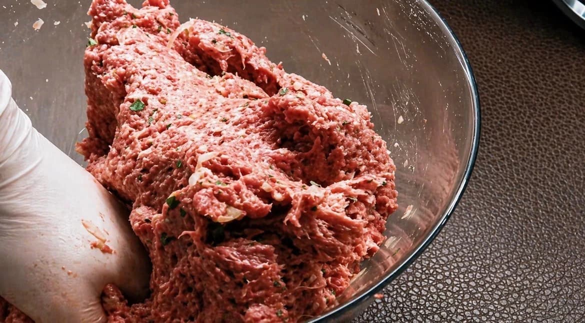 Krydret kjøttdeig blandes for hånd med løk, persille og krydder.