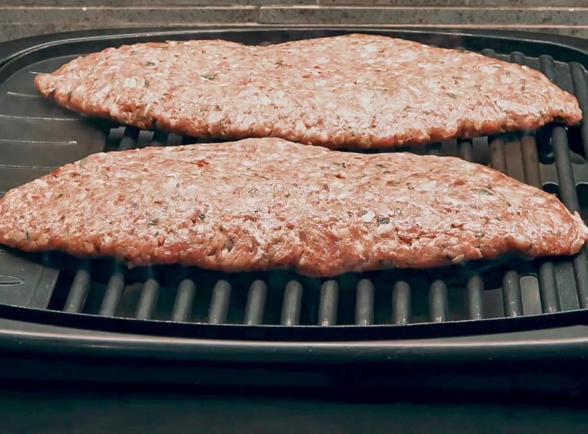 Kjøttstykker med fetaost grilles på en varm grill til de blir gjennomstekte.