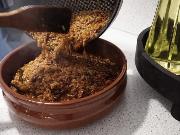 Gresk giouvetsi med orzo og storfekjøtt helles fra en stekepanne over i en ildfast leirform.