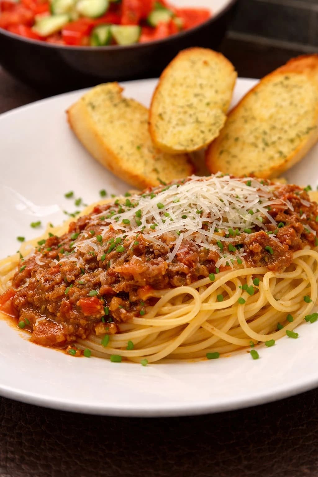 Spaghetti med rask bolognese-kjøttsaus, revet ost og ristet brød ved siden av.