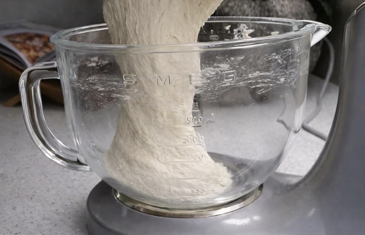 Deig til ciabattabrød løftes ut av bakebollen etter elting.
