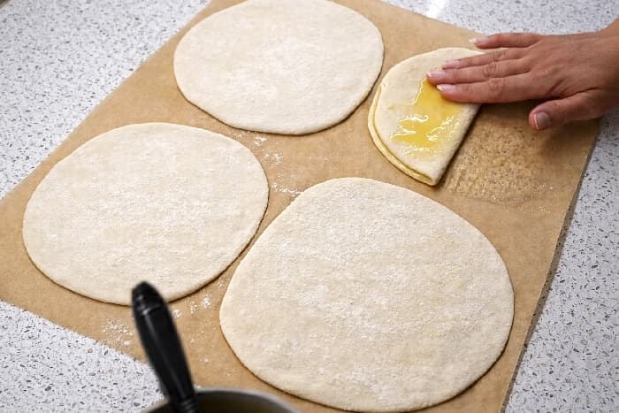 Utrullede deigleiver pensles med smeltet smør og olje før de brettes sammen til burek.