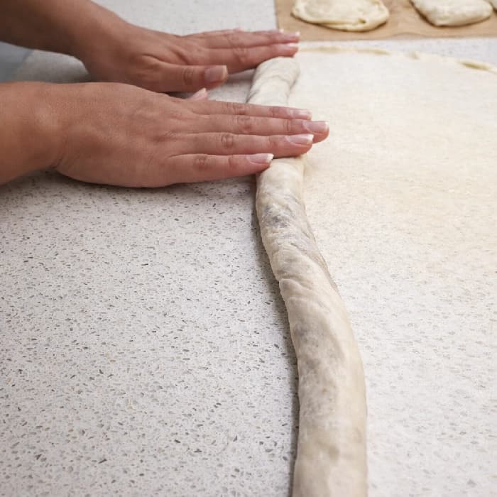 Deigen rulles forsiktig sammen til en lang rull med kjøttfyll inni, klar til å formes til burek.