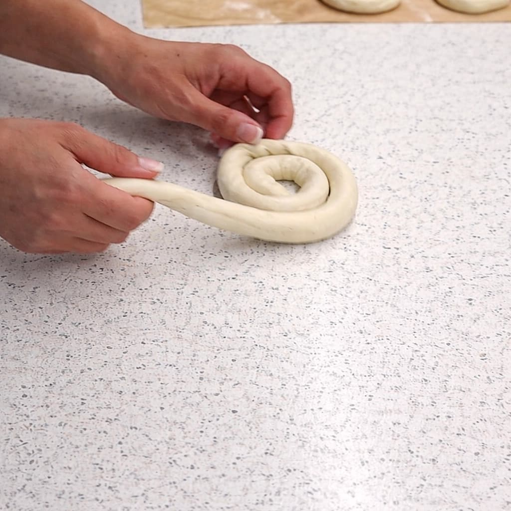 En fylt deigrull formes til en spiral for å lage hjemmelaget burek med kjøttdeig.