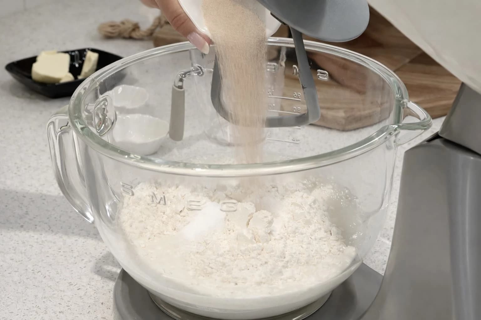 Hvetemel helles i kjøkkenmaskinens bakebolle for å lage hjemmelagde hamburgerbrød.