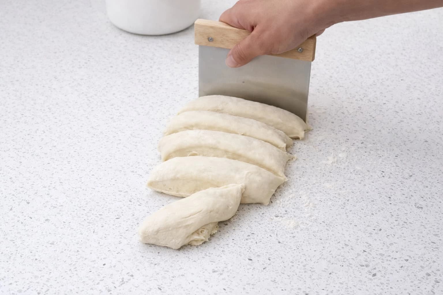 Deigen deles i like store emner med en deigskrape før hamburgerbrødene formes.