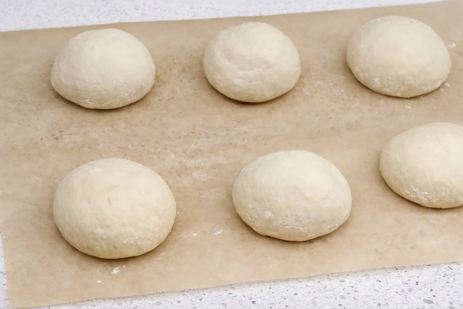 Runde deigemner til hjemmelagde hamburgerbrød legges på bakepapir før etterheving.