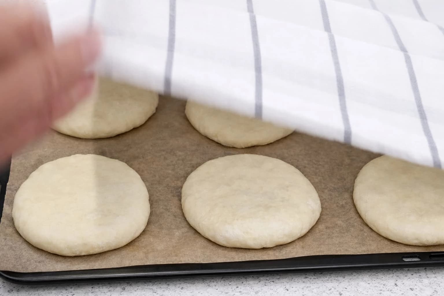Hamburgerbrødene dekkes med et rent kjøkkenhåndkle før videre heving.